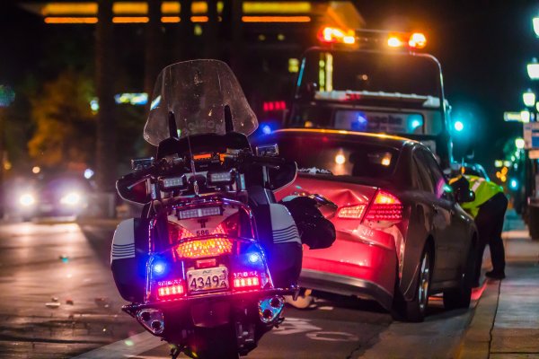 crashed car being looked at by a police officer